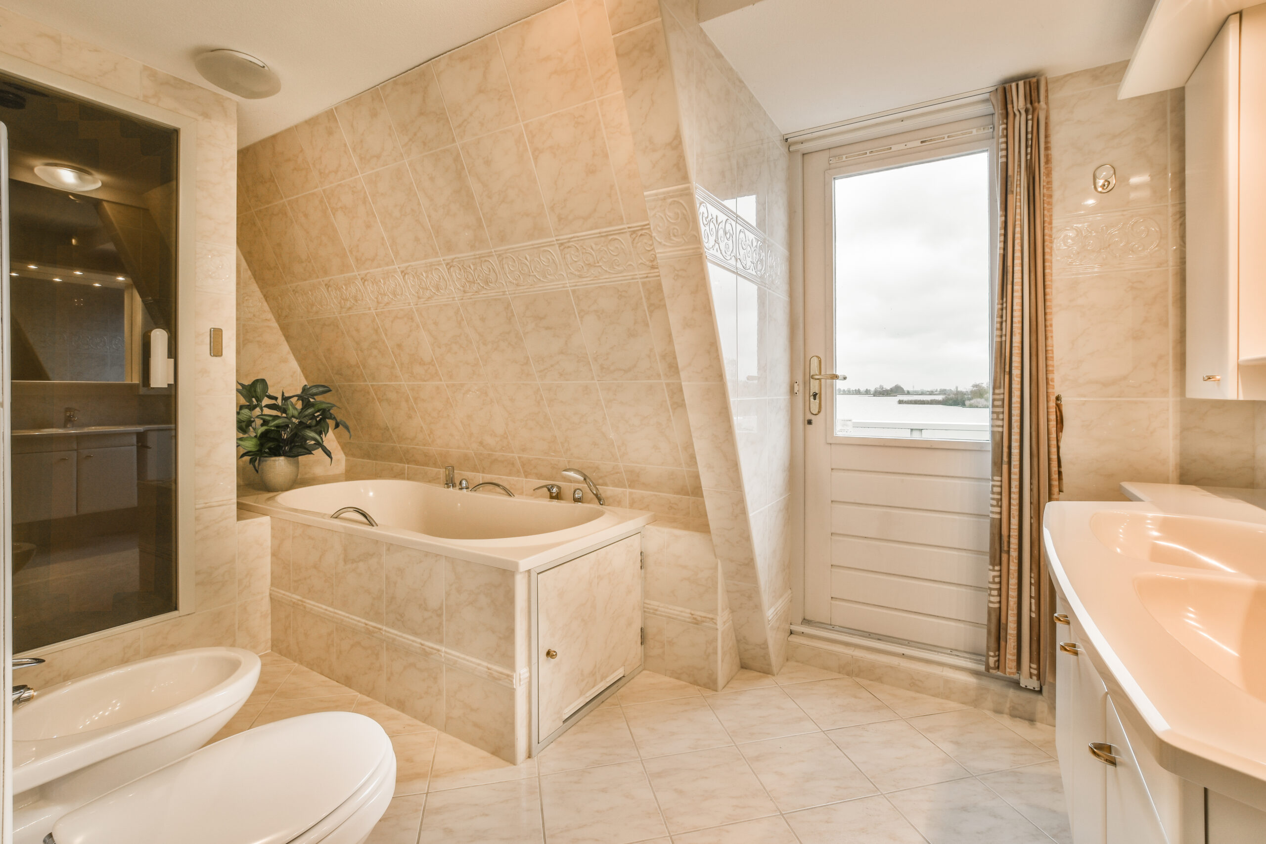 a bathroom with a toilet, sink and mirror in the corner next to the bathtub there is a plant on the wall