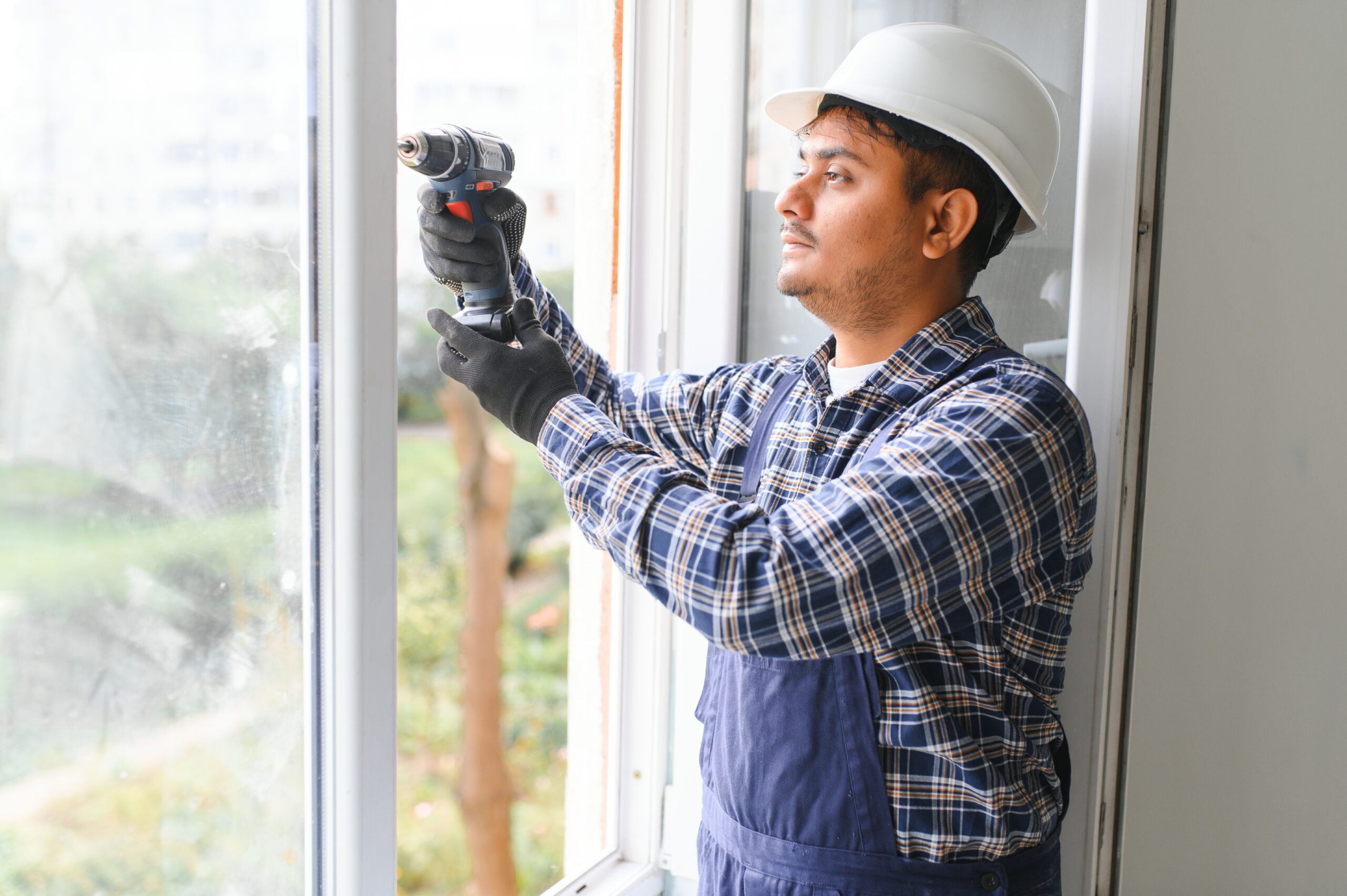 service man installing window with screwdriver.